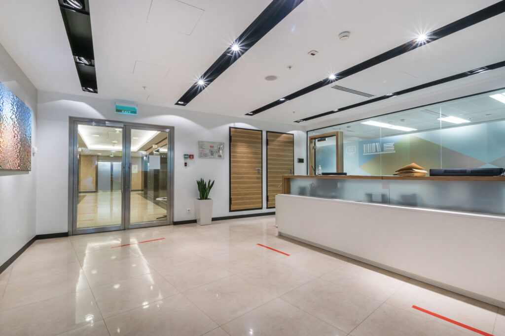 A spacious, bright office hall with a reception desk, glass door